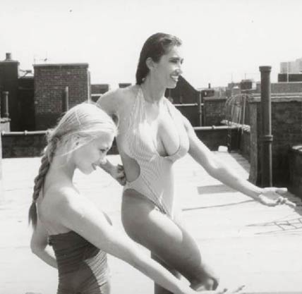 The modern day Amzaon  Mother & Daughter. Bodybuilding photo of a young girl and her Mother practising karate in bathing suits on a New York City rooftop