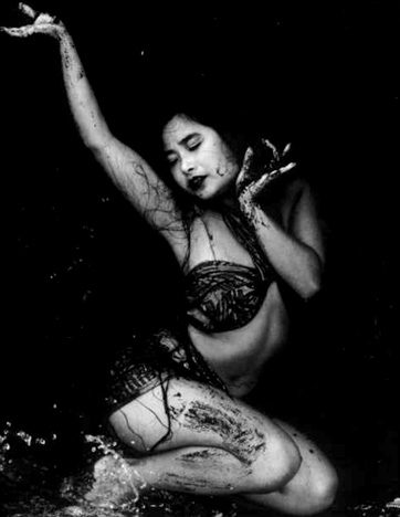 Japanese singer / performer Shakti. Black and white photo of beautiful oriental woman kneeling in shallow water, with dirt on thighs in servitude to the heavens.