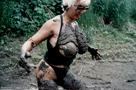 Powerful topless blonde astonished by having been slung at with mud. Large breasts covered by sticky mud.
