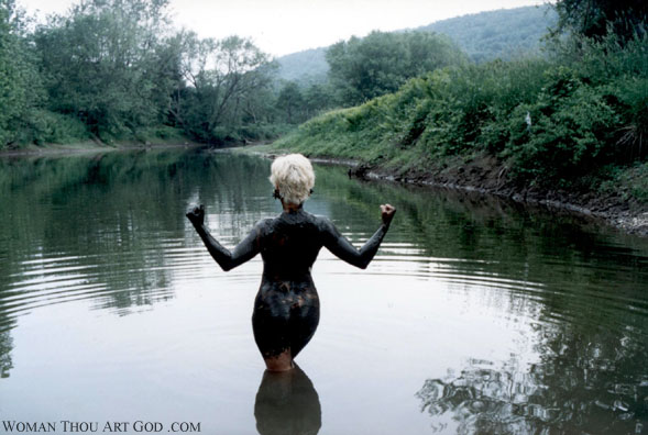 Rear shot of muscle woman covered from head to toe in black mud descending into the tranquil island waters